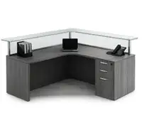 Grey corner reception desk with glass top and storage.